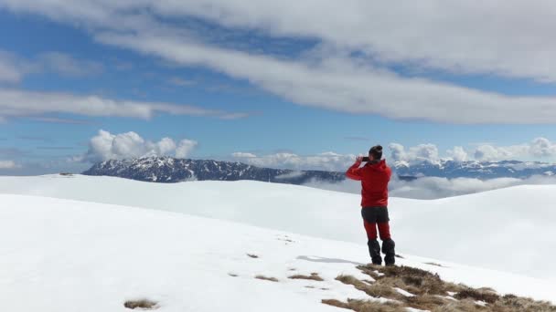 一名男性徒步旅行者在高清阳光下拍摄雪山山脉的照片