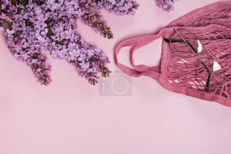 Spring composition with purple lilac flowers, string bag and glasses.