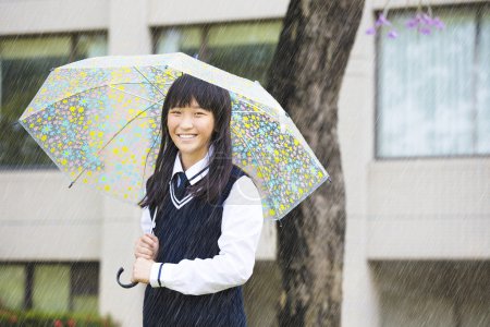  漂亮的学生打着伞在雨中的女孩