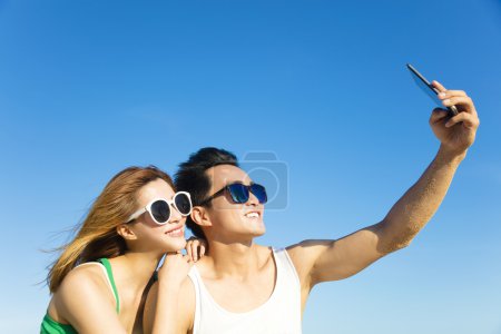 Young couple taking vacation selfie photograph at the beach