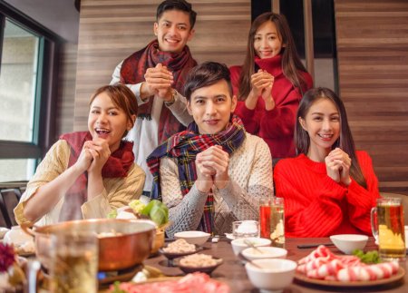 happy chinese new year, young group greeting with congratulations gesture in restaurant