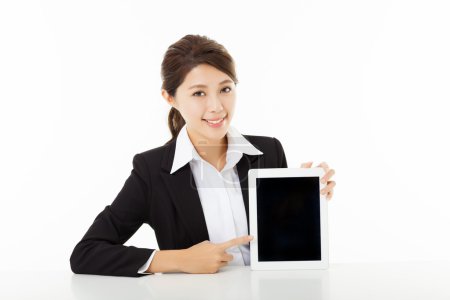 Smiling young businesswoman showing and pointing to the tablet