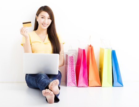 Smiling young woman shopping with laptop