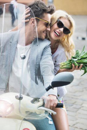 可爱的女人和她的男朋友坐在滑板车上