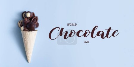 世界巧克力日和蓝色背景华夫饼筒中的巧克力李子  