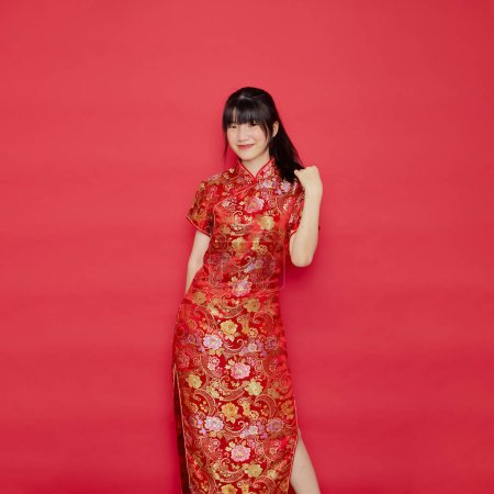 Cute young Asian woman wear cheongsam with action for Chinese new year concept on a red background