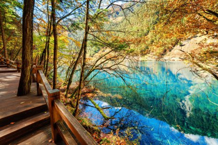 Fantastic azure lake among colorful fall woods. Autumn landscape