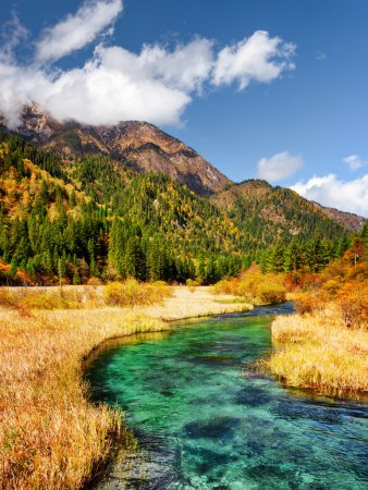 Beautiful river with azure crystal clear water among fall fields