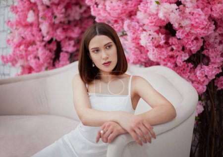 Young girl in a white dress on the background of spring flowers