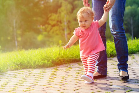 first steps of little girl with mother outdoors