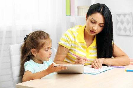 Beautiful school girl doing homework with mother at home