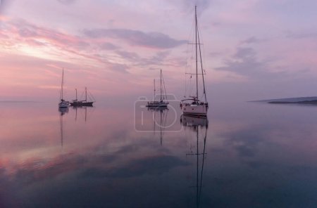 Moored sailboat early in the morning in the bay before sunrise