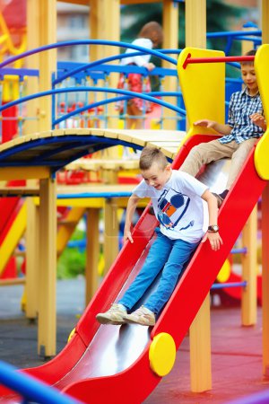 group of happy kids sliding on colorful playground