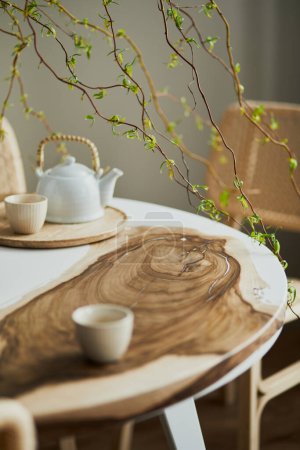 室内设计时尚的餐厅内部与家庭木制和环氧树脂表，藤椅，花瓶花和茶壶与杯子。细节。模板.