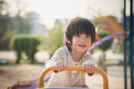 孩子骑在阳光下游乐场跷跷板板