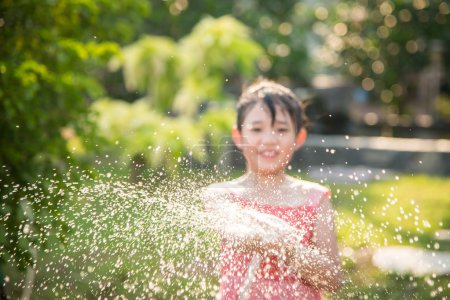 模糊的亚洲小孩在玩水软管