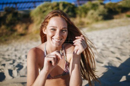 红头发的女孩在海滩上抽烟