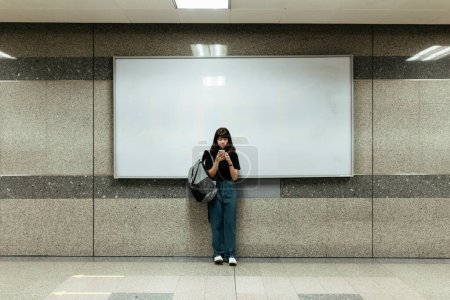 Asian thai backpacker woman using smartphone infront of white blank copy space.