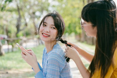 野餐时，黄色T恤衫女做蓝色T恤衫女的发型设计.