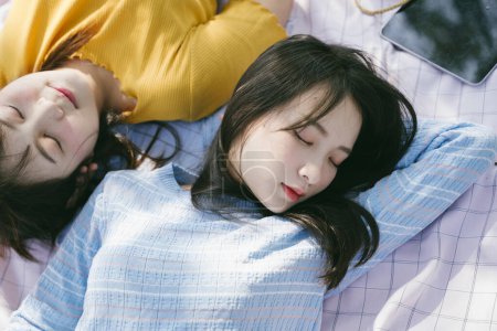 两个女孩在户外野餐时睡在垫子上.