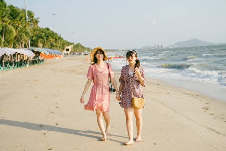 两个女孩周末一起在海滩上散步.