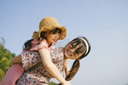 在阳光明媚的日子里，戴着太阳镜的女孩背着她的朋友在海滩上散步.