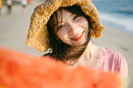可爱的女孩把手中的西瓜伸向摄像机，然后斜着头.