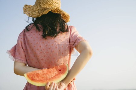 一个长发女人的背影，用乌黑的天空把西瓜放在她的后面.