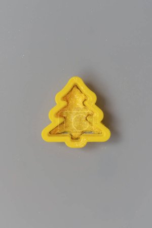 Christmas tree yellow plastic cutter on gray.