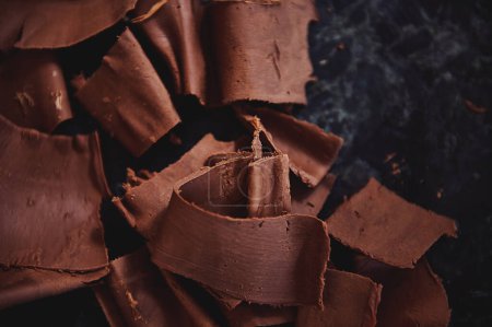 平铺的组成与冷却巧克力质量收集与糖果刮胡刀在大理石表面。世界巧克力日