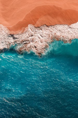 Beautiful sandy beach with blue sea, vertical view. Drone view of tropical blue ocean beach Nusa penida Bali Indonesia. Lonely sandy beach with beautiful waves. Sandy beach wallpaper. Copy space