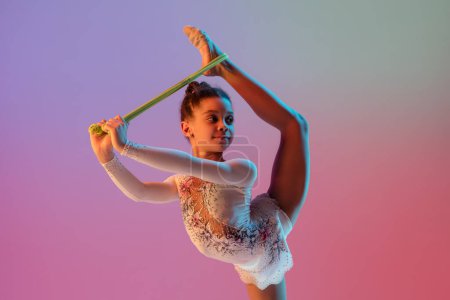 African-american rhythmic gymnast, pretty girl practicing on gradient studio background in neon light