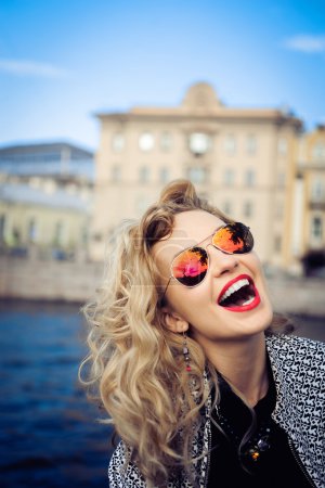 Young girl in sunglasses posing against the backdrop of the city