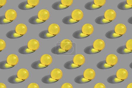 Round yellow pills on gray background. Vegan vitamin C. Organic nutrition, oil. Skincare beauty supplement. Pattern with gelatin capsule. Pharmacy health care concept.