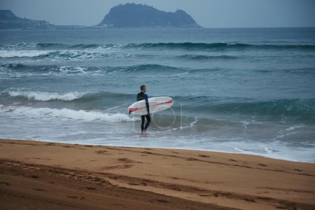 surfer in wetsuit walking into water