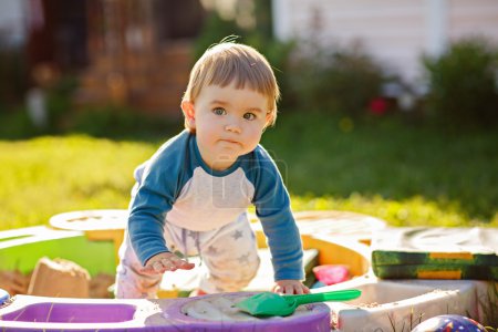 Little chubby toddler boy playing in the sandbox in the summer in Sunny weather