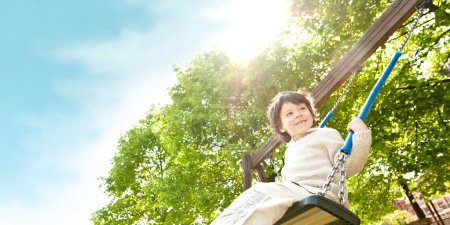 beautiful male kid play on swing in a park 