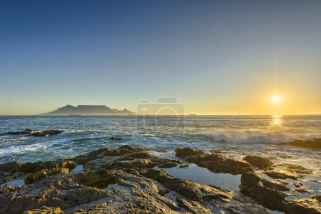 Cape Town Table Mountain's iconic flat top seen from Blouberg Strand in South Africa during sunset.