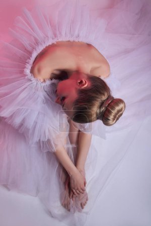 Beauty Woman bright red makeup sits on the floor. Art Girl in a transparent light dress on a pink background. Professional bright makeup woman