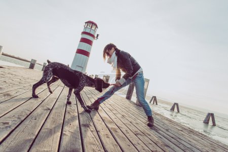 美丽的年轻女子，在海边和狗一起玩