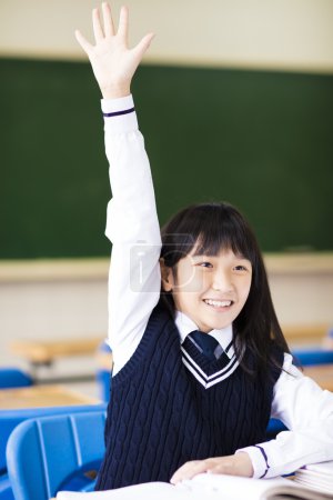 快乐的年轻学生女孩举起手拿着本书