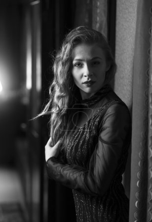 Portrait of sexy woman in vintage dress posing at hotel hallway