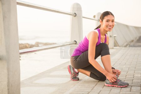 Smiling fit woman tying shoelace