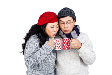 Happy couple blowing on cups