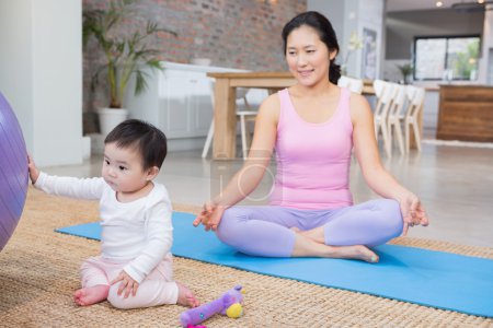 Calm mother sitting on mat at home