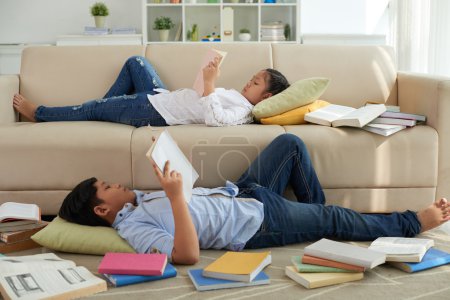 Children lying on sofa and reading books