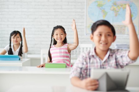 Children rising hands up to answer question