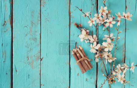 Image of spring white cherry blossoms tree next to wooden colorful pencils on blue wooden table