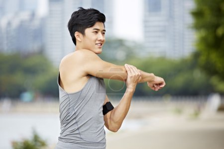 Young asian man stretching arms