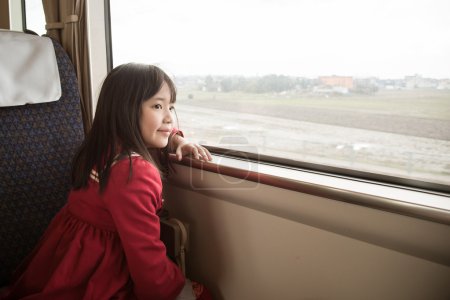 Little asian girl looking through window. 